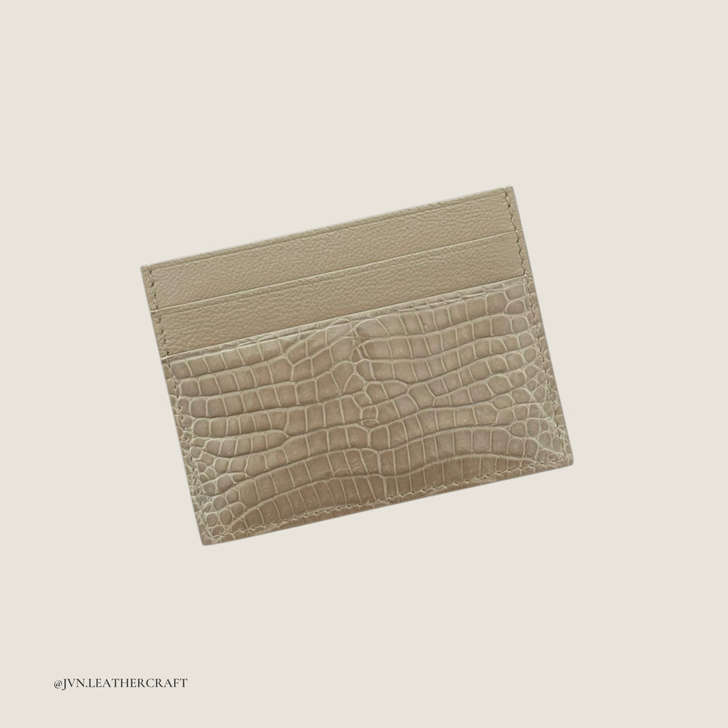 Beige crocodile-textured leather cardholder on a light beige background