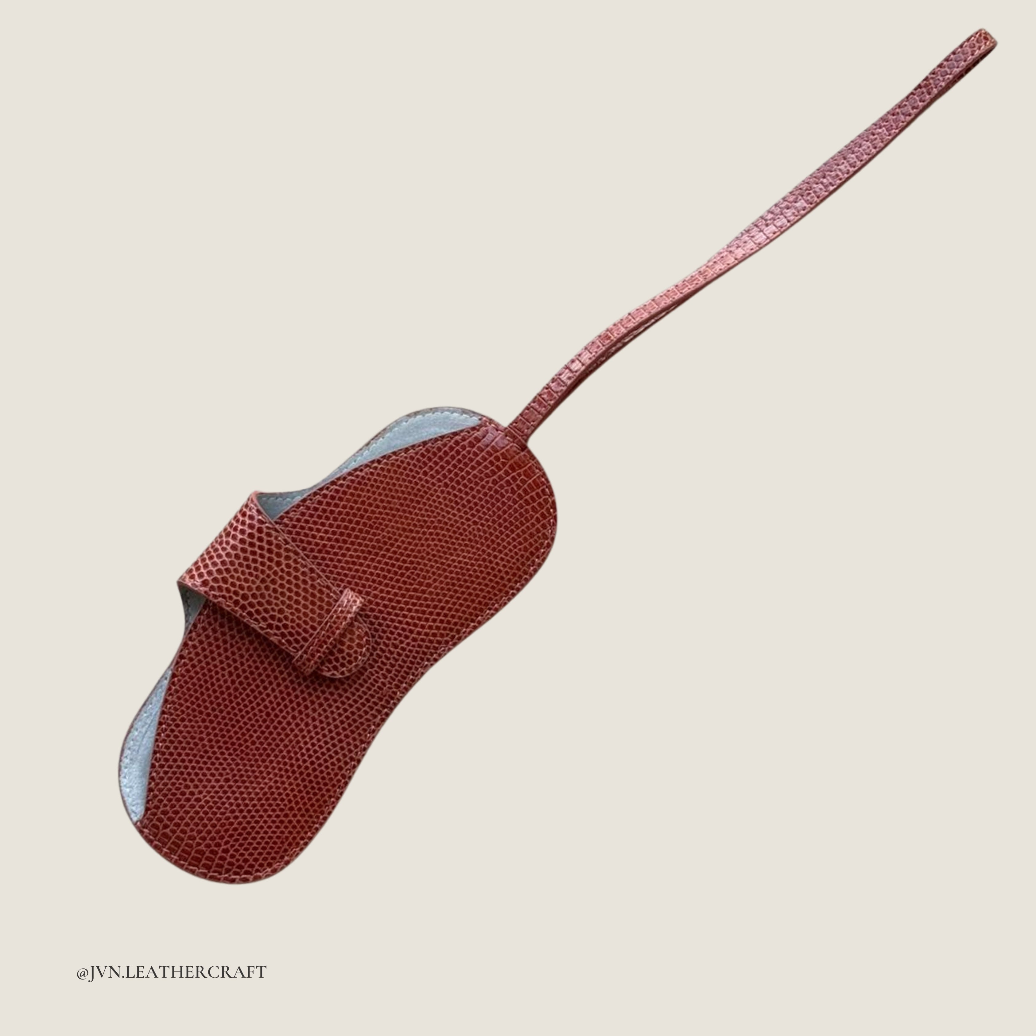 Red lizard with a long handle  branded 'JVN Leathercraft'.